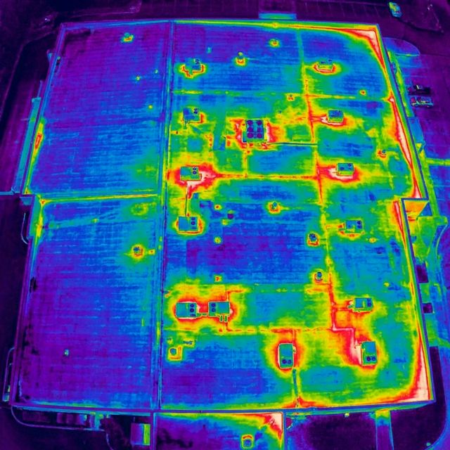 Aerial radiometric thermal scan of commercial building rooftop revealing heat signatures and energy loss