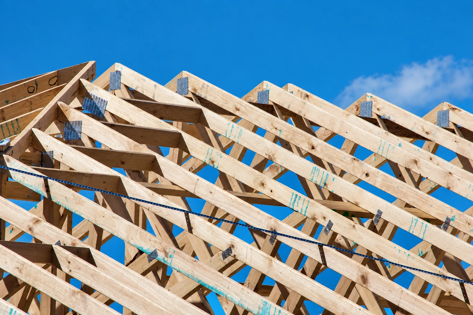 Timber roof trusses against a clear blue sky