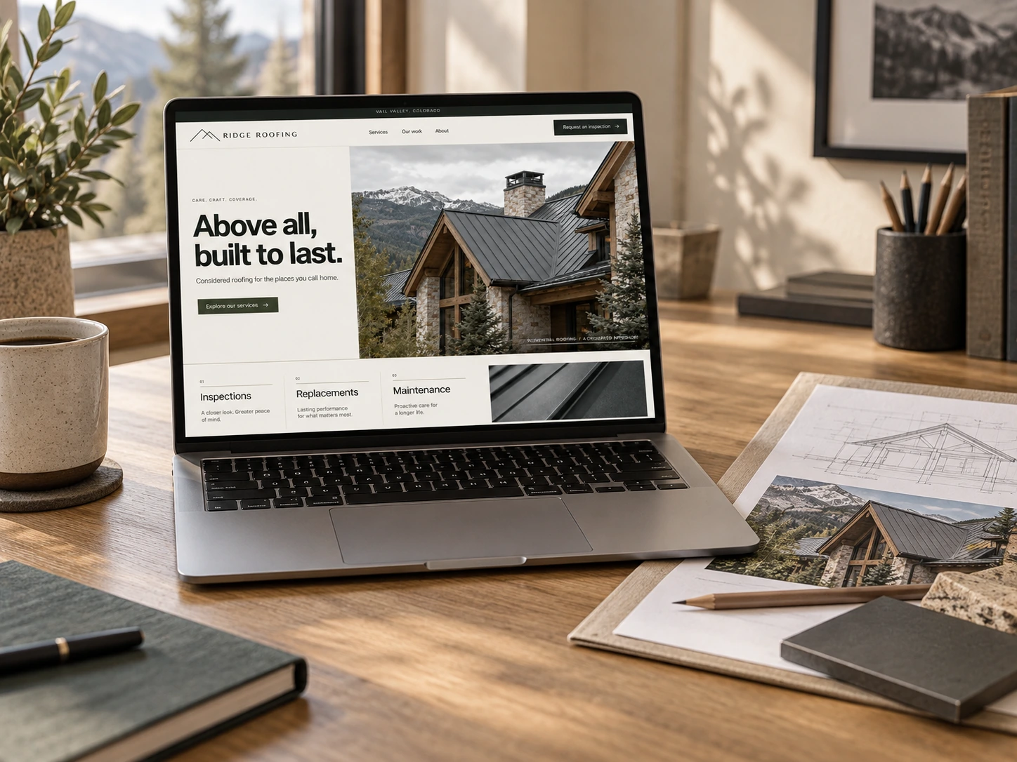 Ridge Roofing website on a laptop at an oak desk beside architectural drawings, a roof photograph and material samples